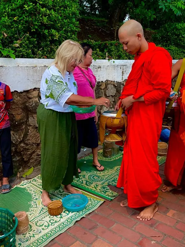 Maru entregando su ofrenda a los monjes en Luang Prabang